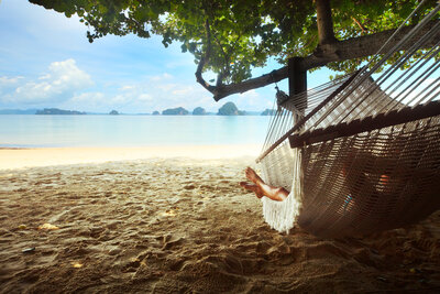 A person relaxing in a hammock at the beach